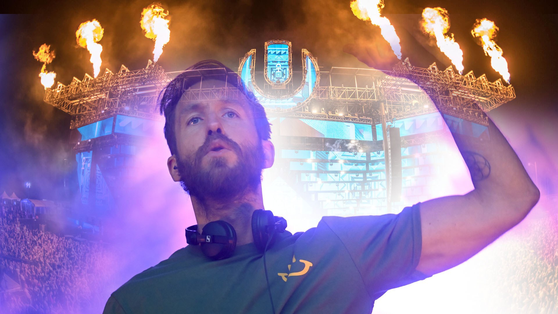 Calvin Harris in a green t-shirt and headphones raises an arm before a stage with flame jets and the Ultra logo.