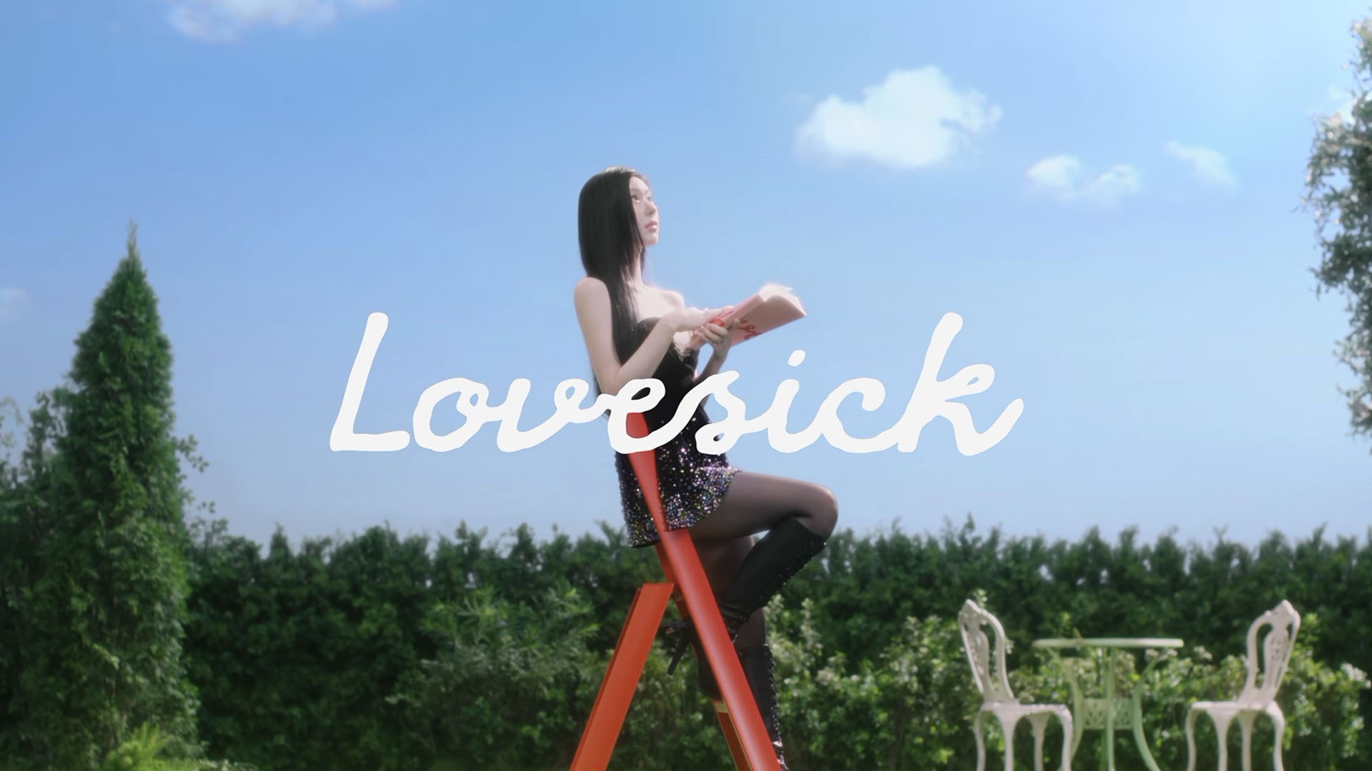 CHAERYEONG en robe noire scintillante et bottes lit un livre rose sur une échelle rouge dans un jardin ensoleillé, sous le mot "Lovesick".