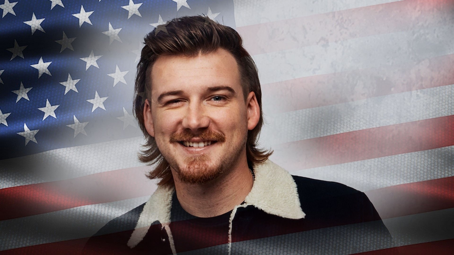 Morgan Wallen wearing a navy jacket with a cream sherpa collar in front of an American flag.