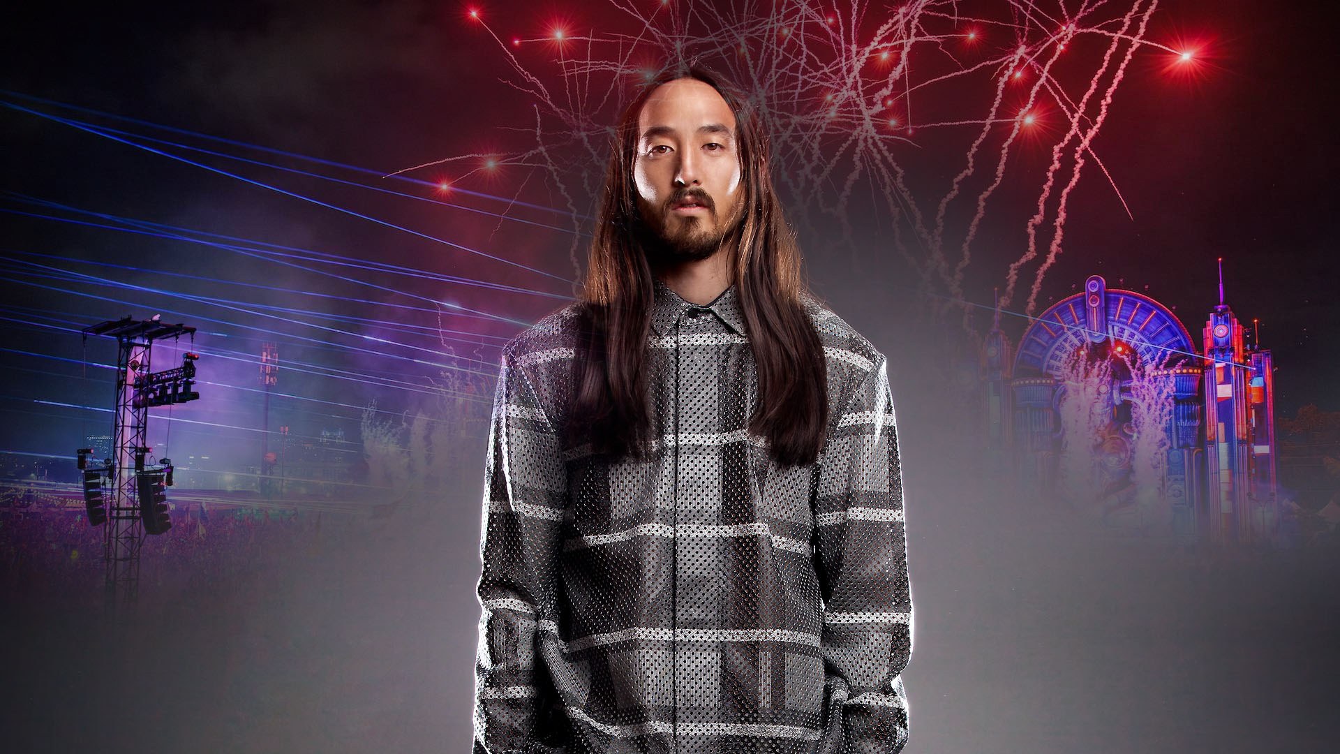 Steve Aoki in a geometric patterned jacket against neon-lit EDC festival stage structures and electric effects.
