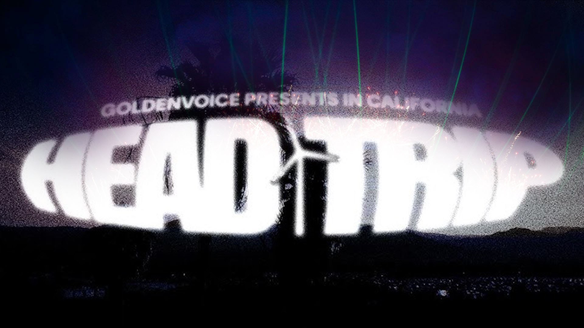 Texto blanco luminoso "HEAD TRIP" con rayos láser verdes sobre un fondo de escenario morado oscuro.