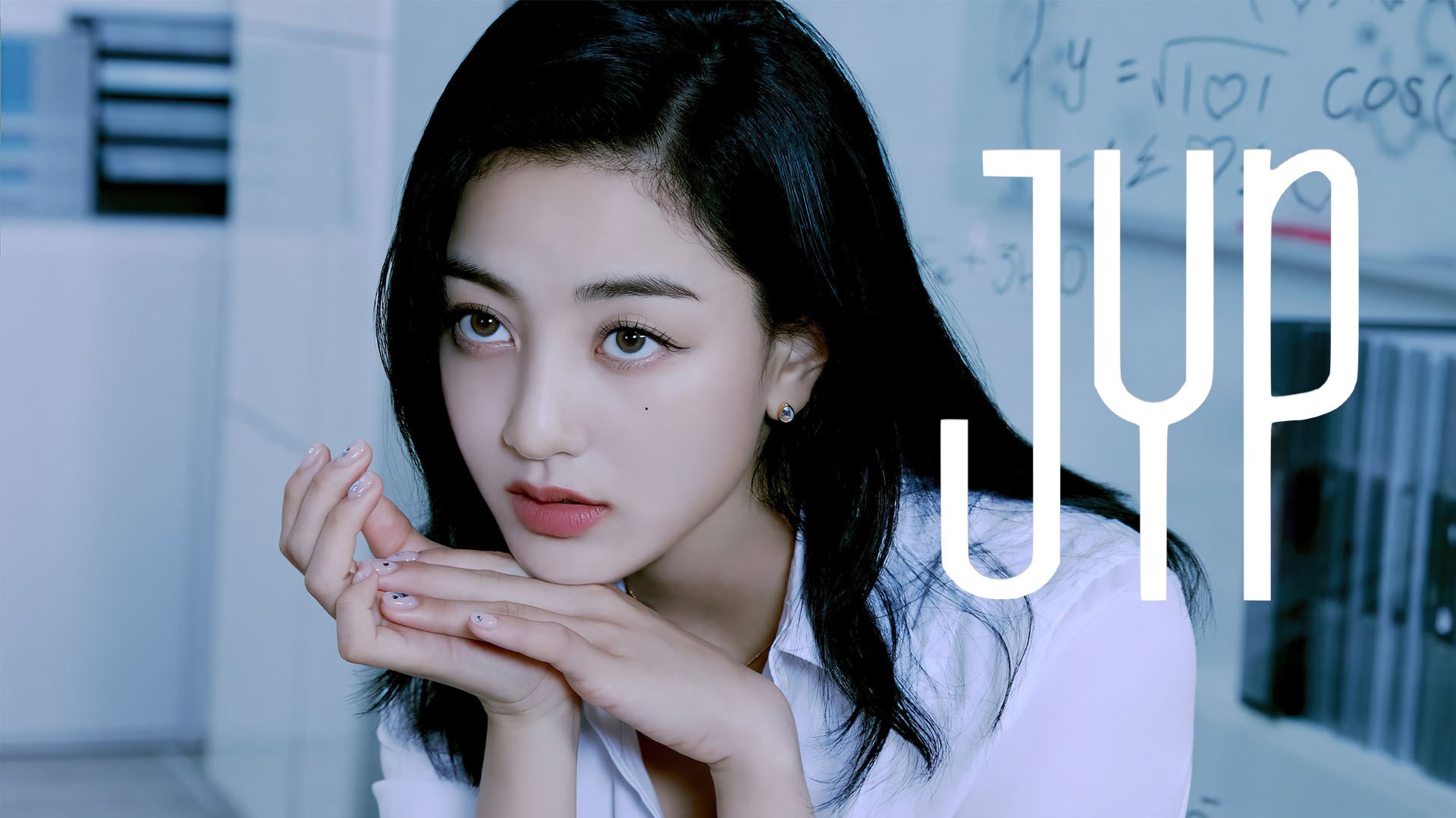Jihyo in a white collared shirt rests her chin on her hands before a chalkboard, with a white JYP logo at right.